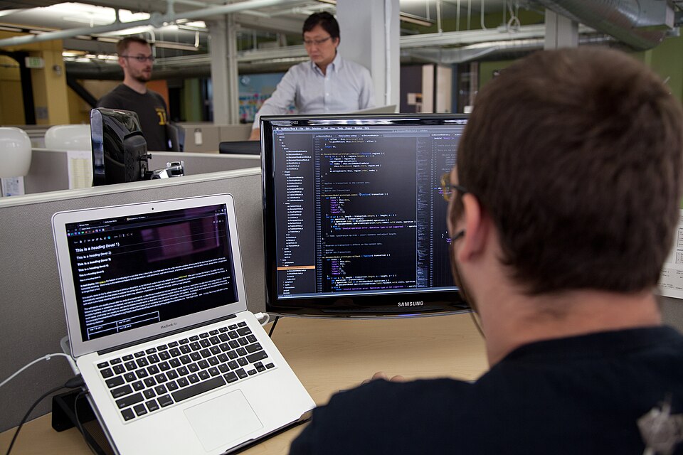 Software developer working at a dual-monitor coding workspace