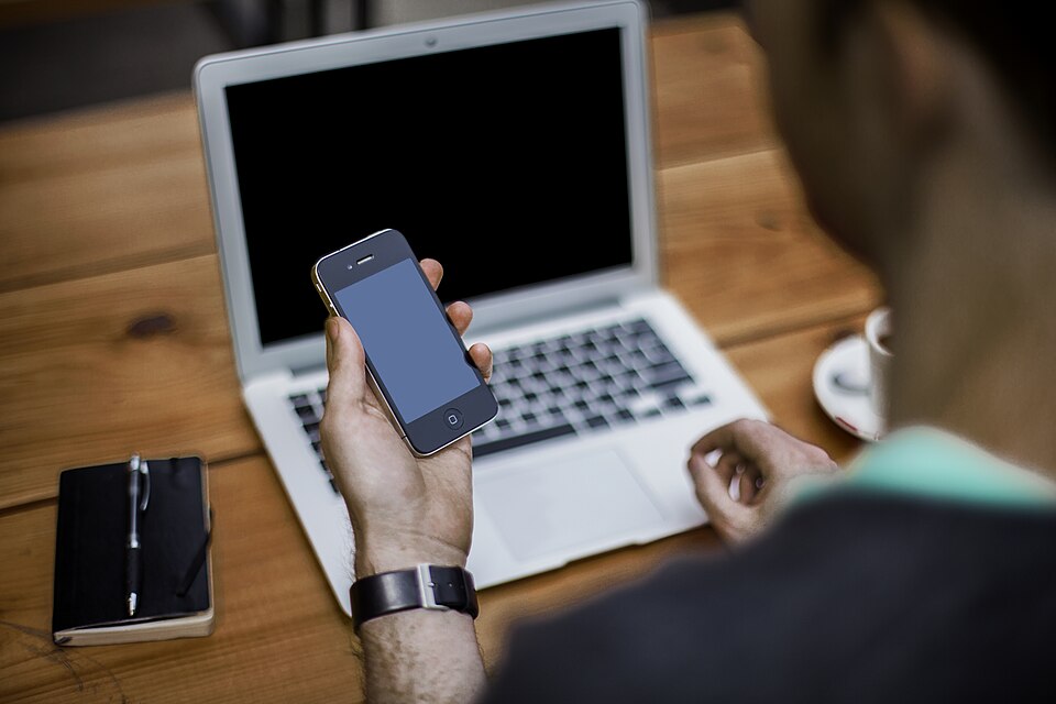 Professional using laptop and smartphone at a modern workspace