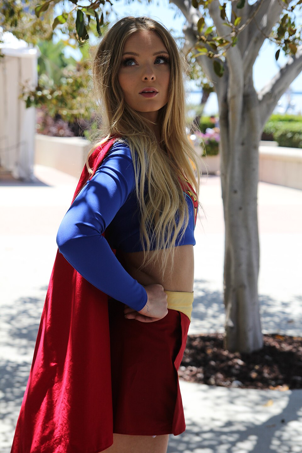 Supergirl cosplayer in iconic blue and red costume at a fan convention